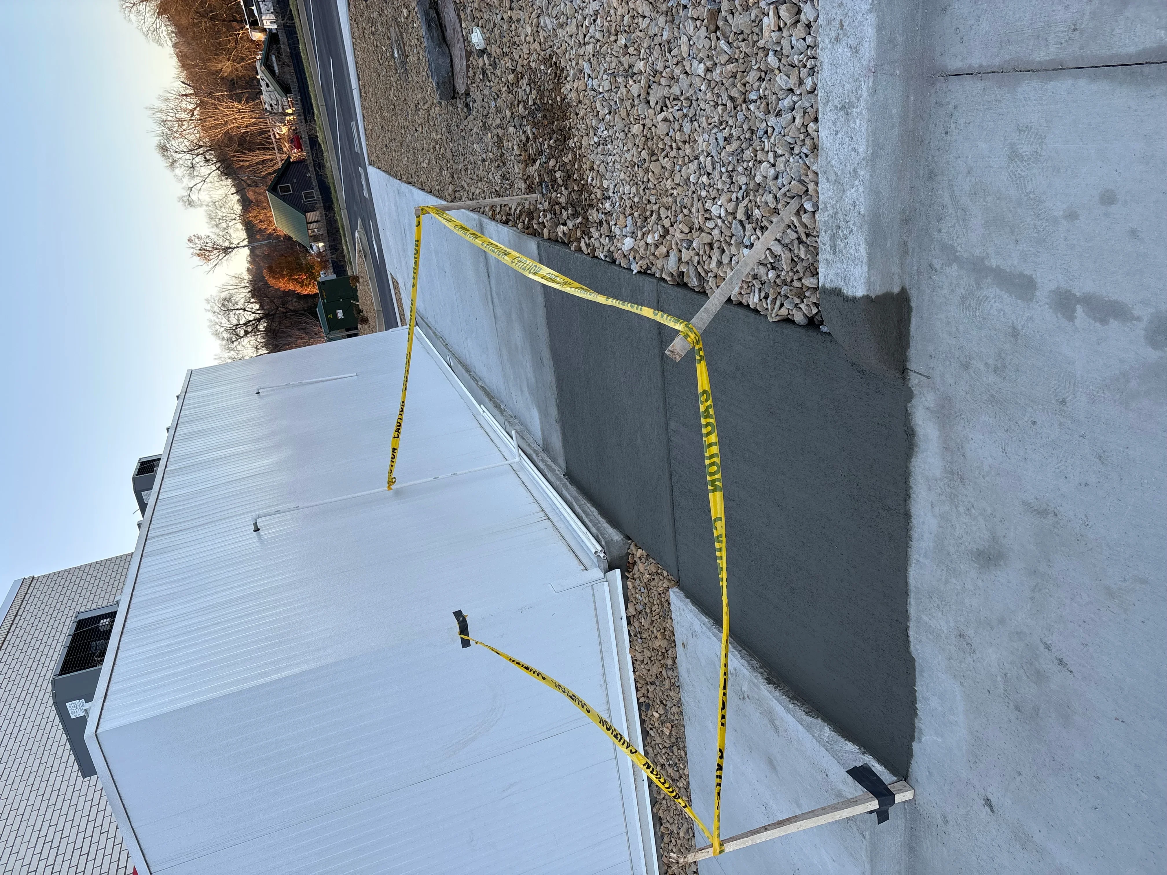 Concrete retaining wall and foundation pad with yellow measuring tape and gravel backfill