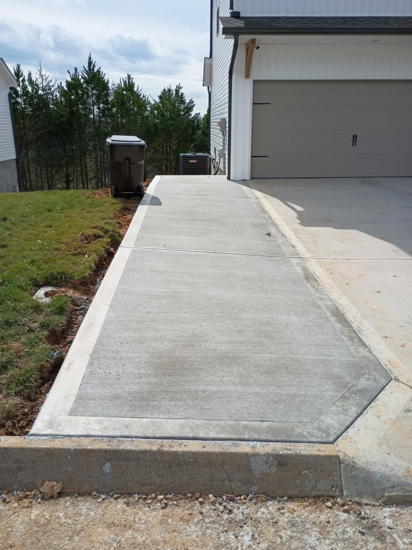 New concrete driveway approach with control joints leading to garage door
