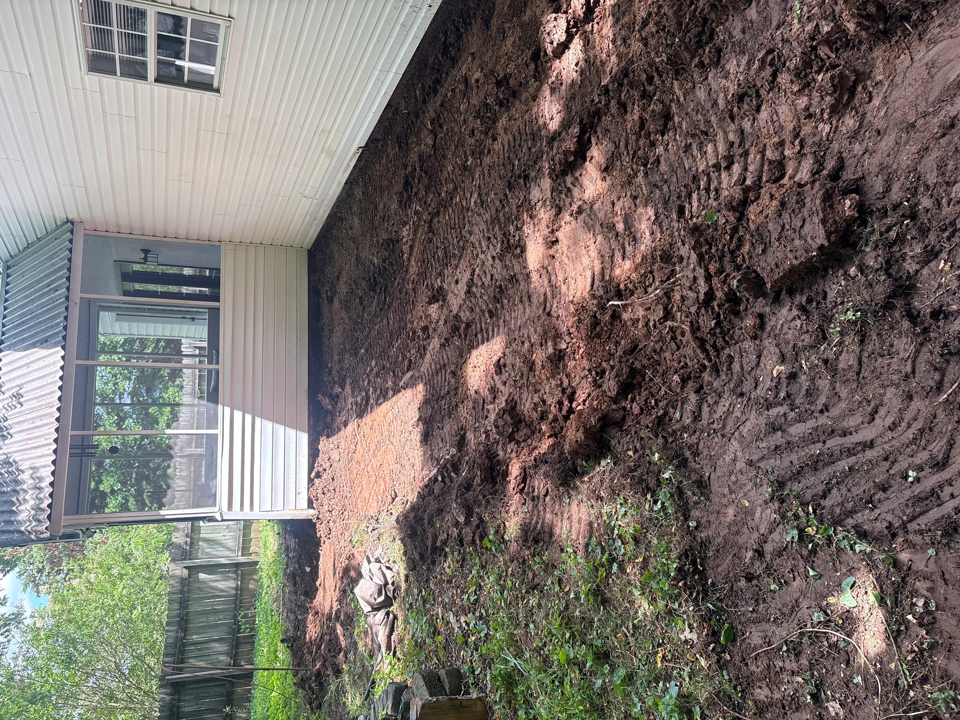 Excavated residential lot with graded earth banks and metal building structure