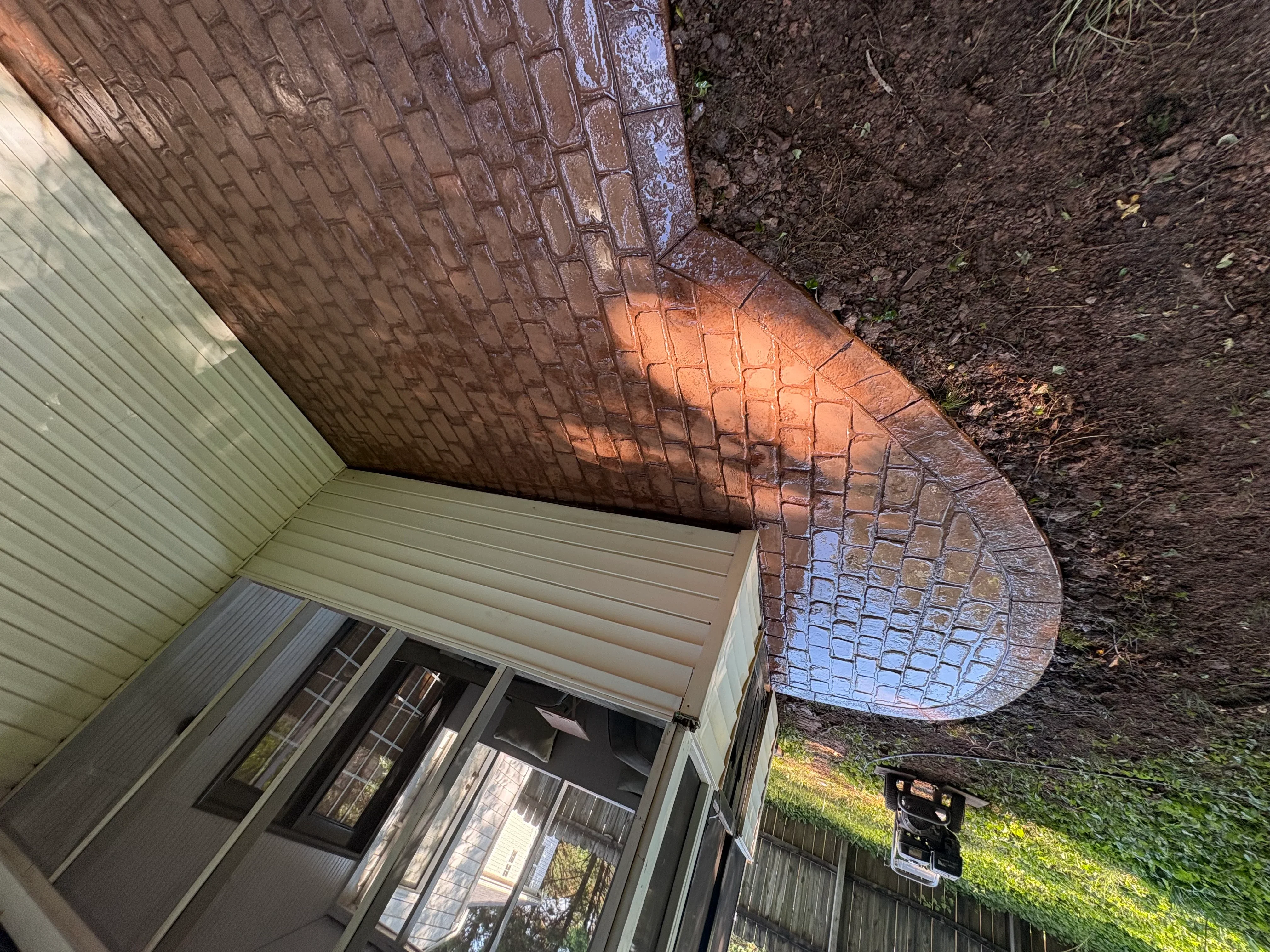 Curved brick patio with running bond pattern installed next to home foundation