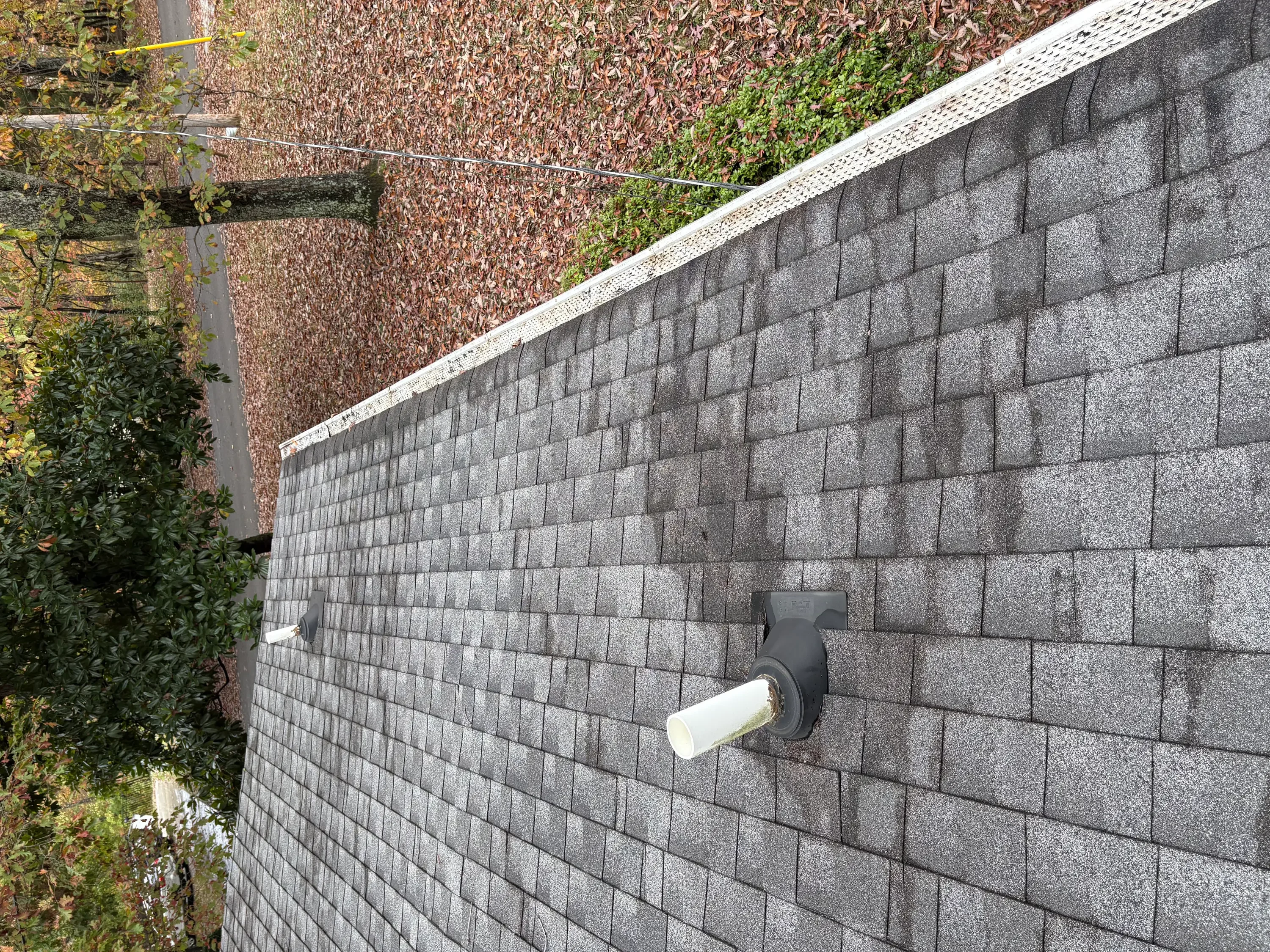 Gray concrete block retaining wall with drainage pipe and white cap trim