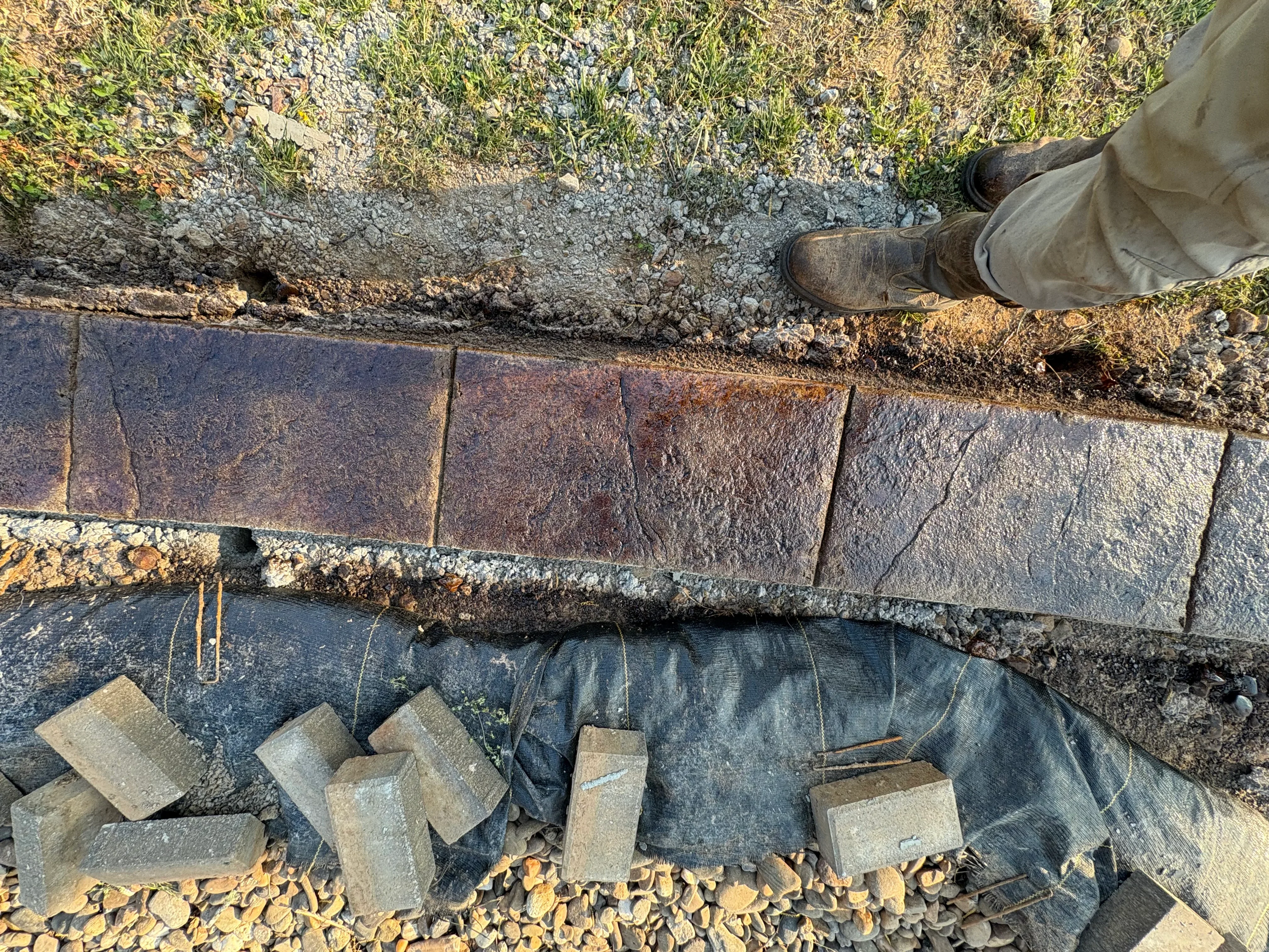 Concrete pavers and landscape fabric base preparation for hardscape edging installation