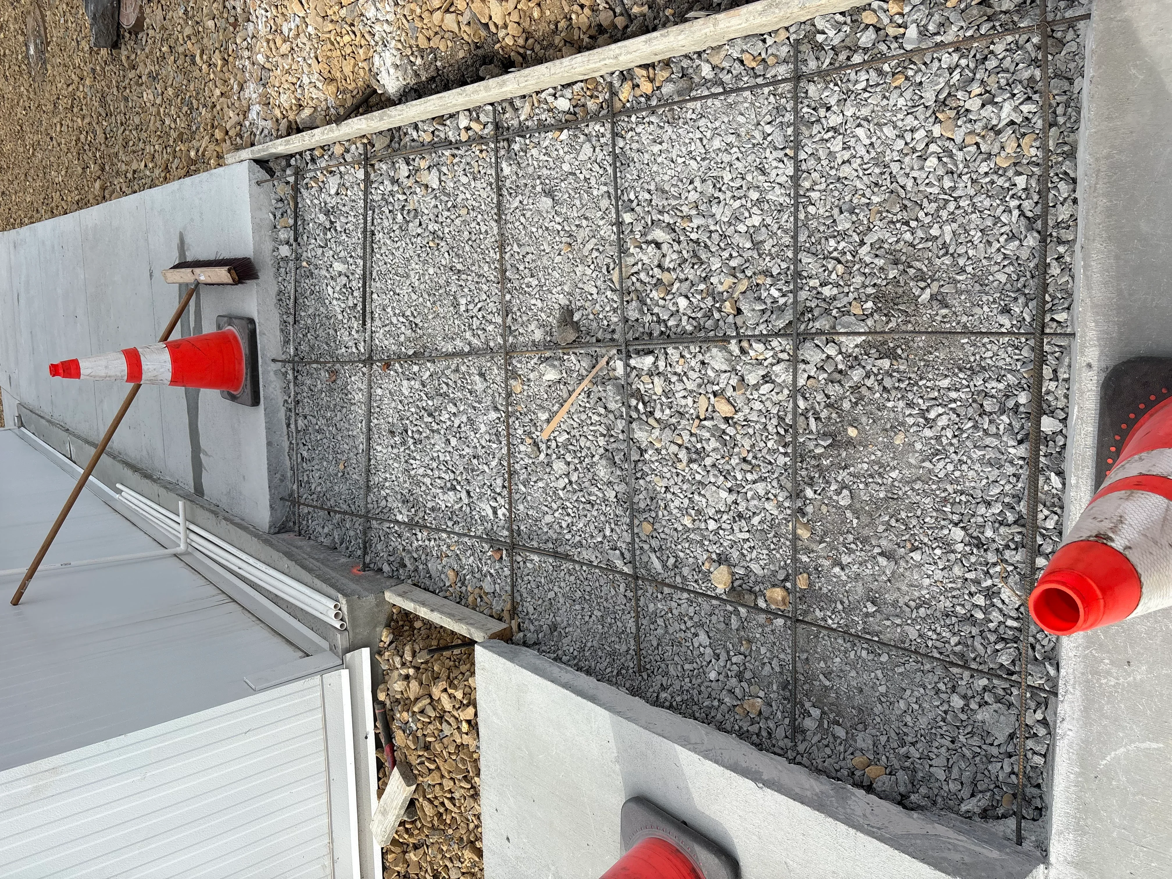 Retaining wall with metal grid reinforcement and crushed stone fill during construction