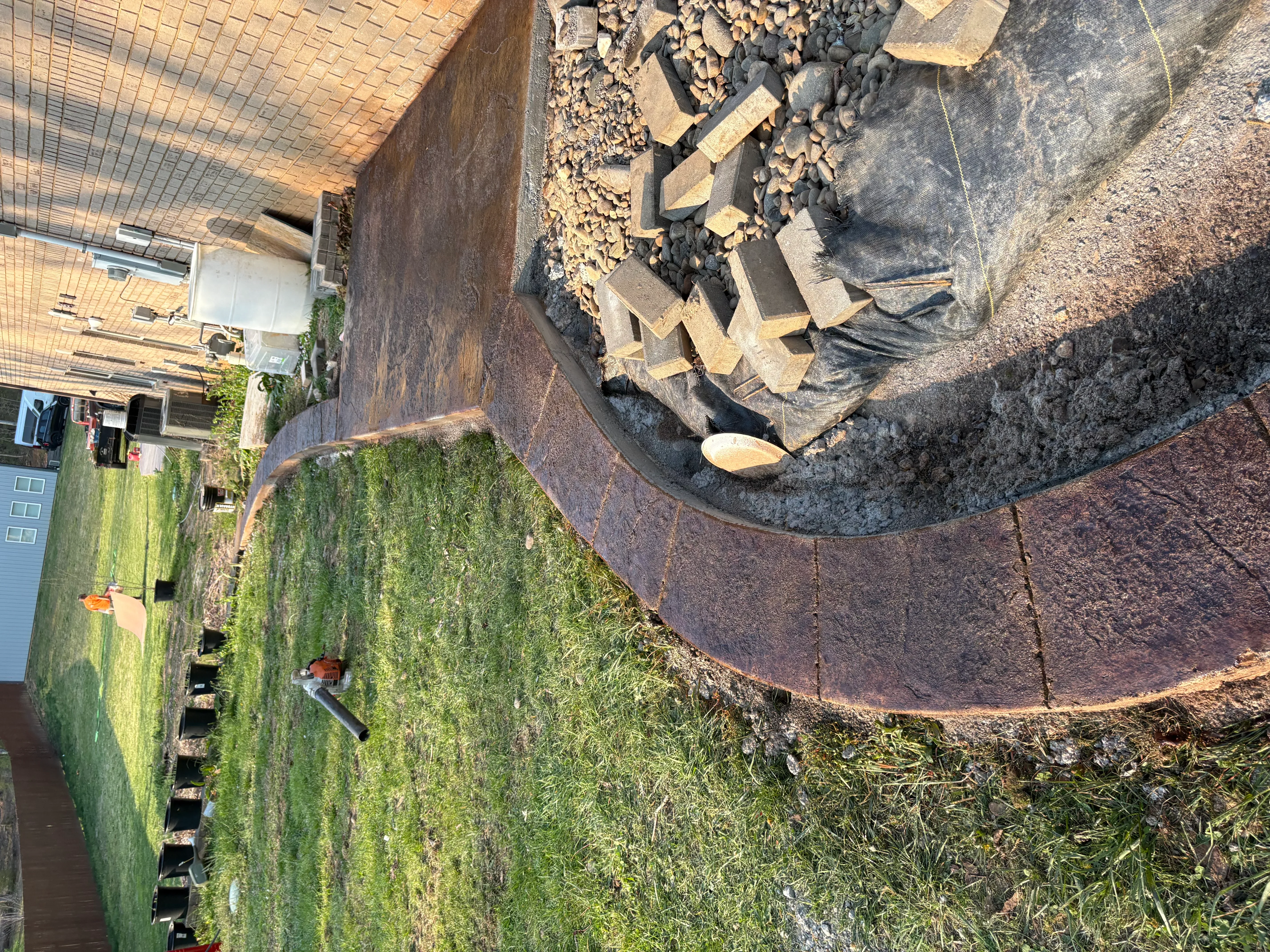 Large circular concrete pad with gravel base and drainage preparation in residential yard