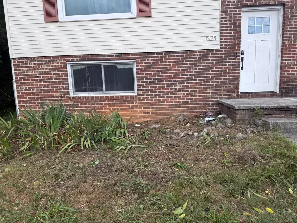 Brick home foundation with concrete work and cleared landscaping bed area