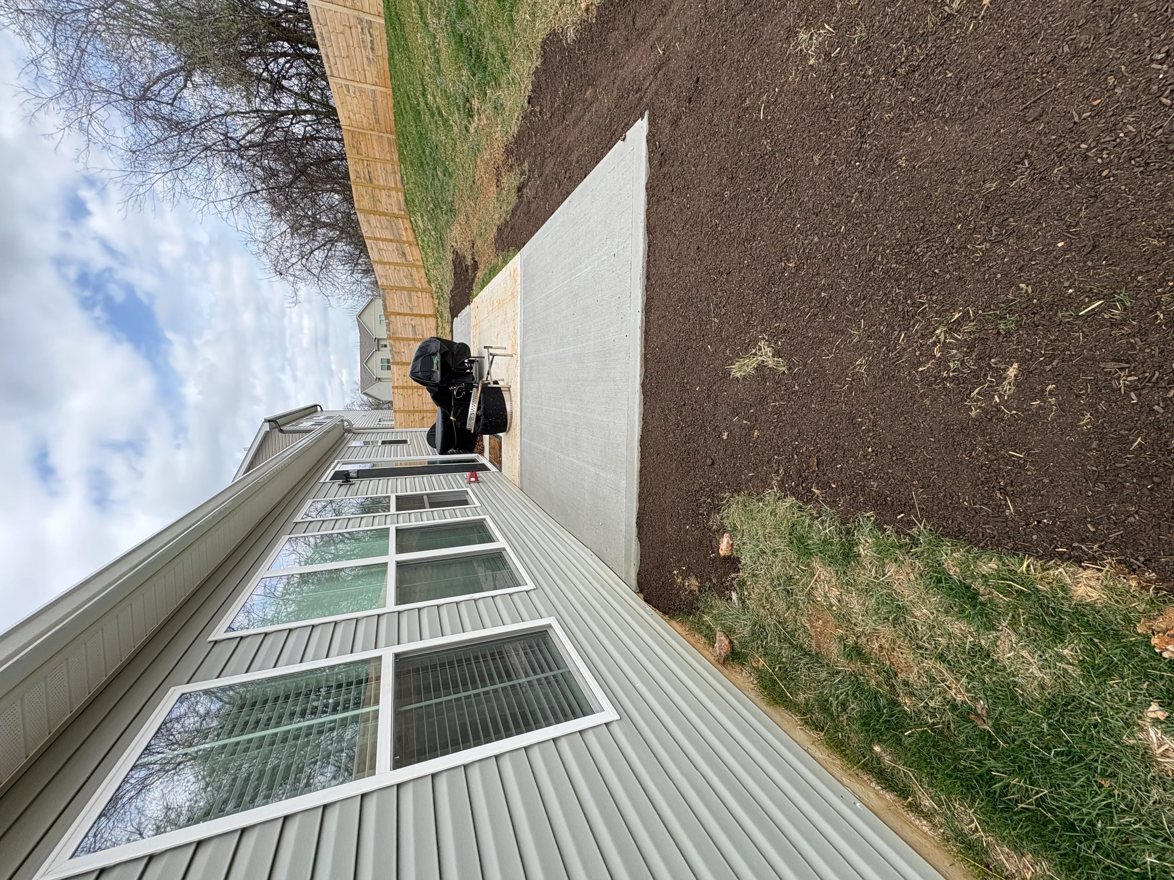Newly installed concrete driveway next to brick home with landscaping
