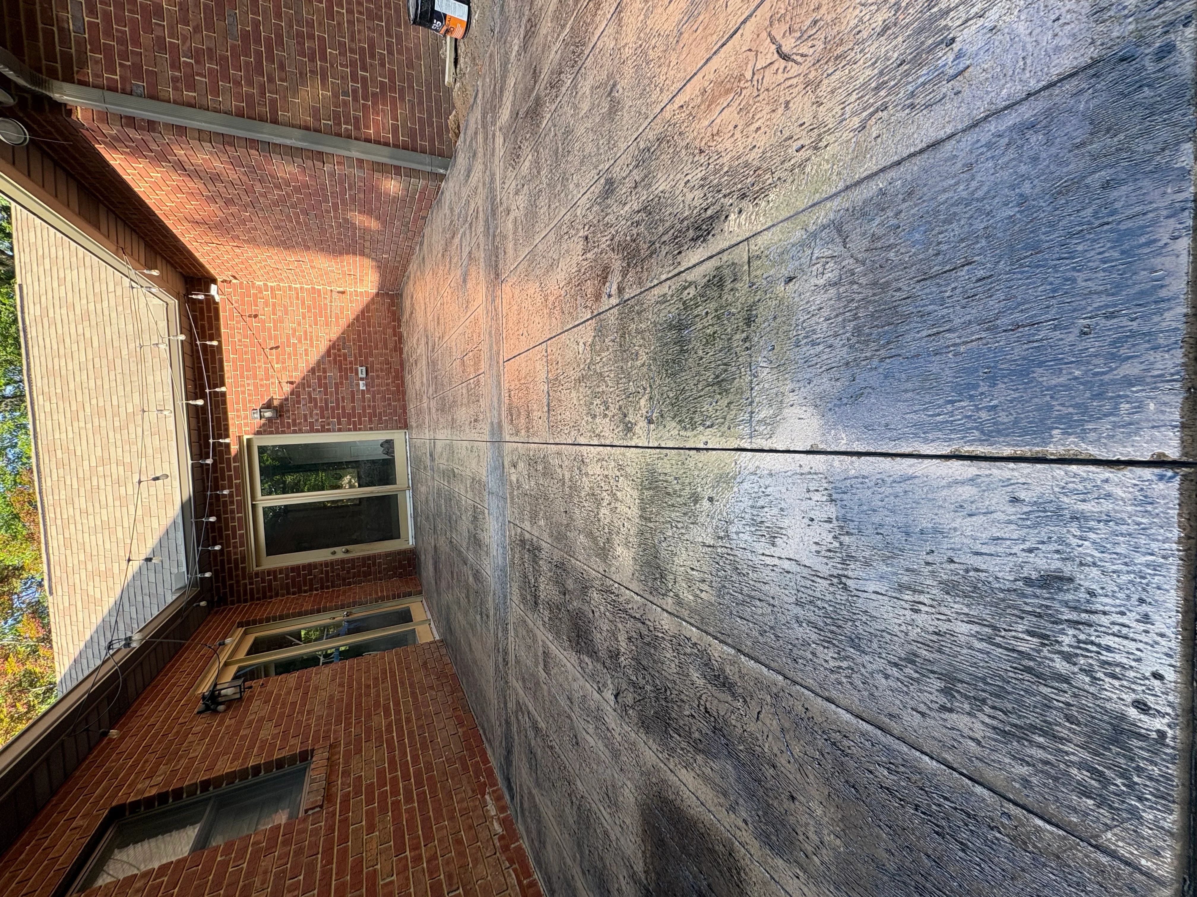 Clean brick patio with pressure-washed stone wall in residential side yard