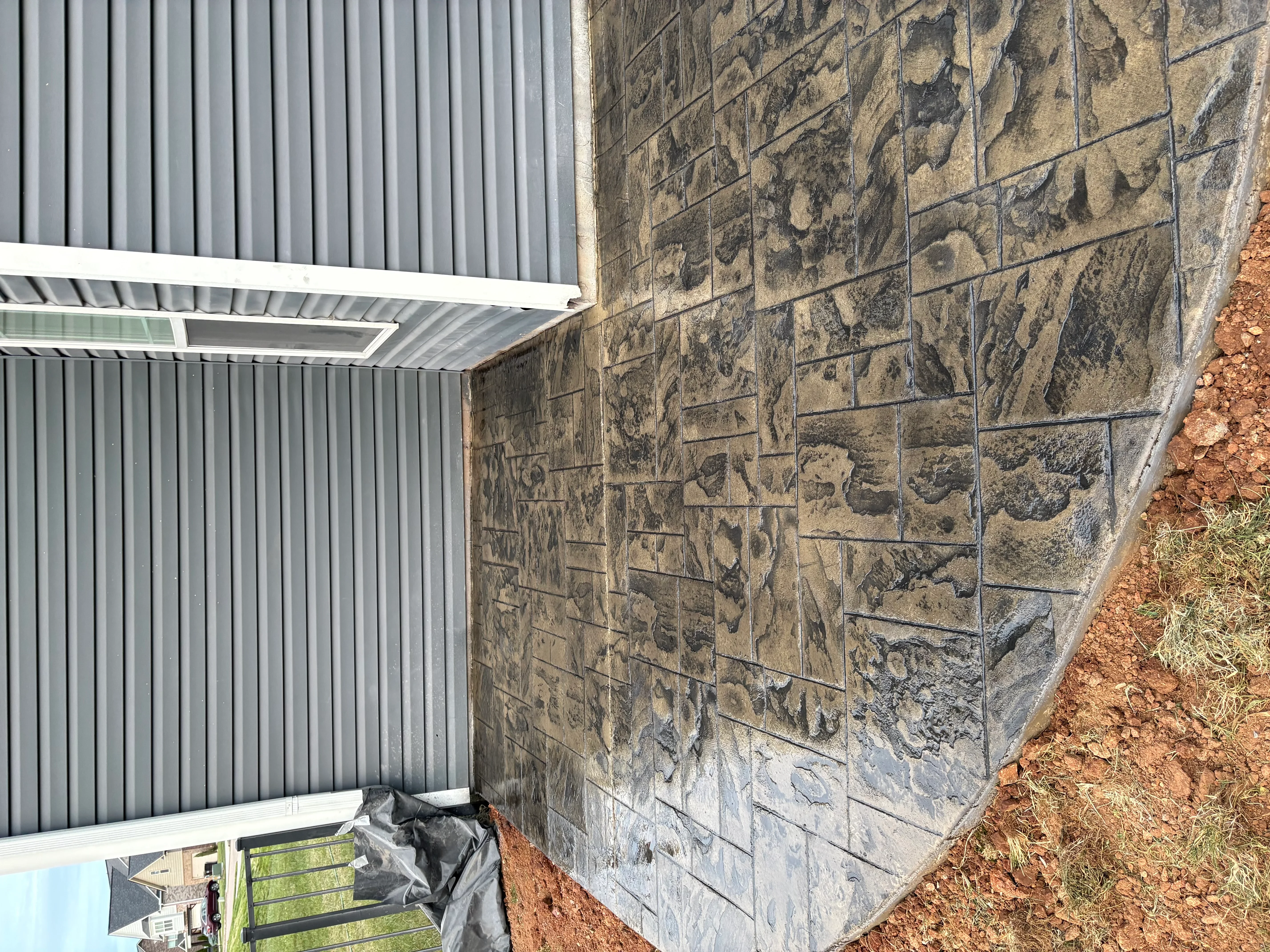 Concrete pad with metal carport roof and corrugated siding on red clay ground